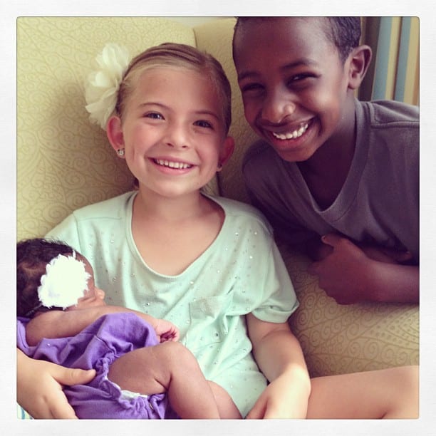 Brother and sister holding newborn. transracial adoptive family. Global Munchkins