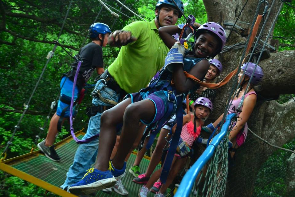 Black boy on zipline in Costa Rica with instructor giving him a push | Global Munchkins