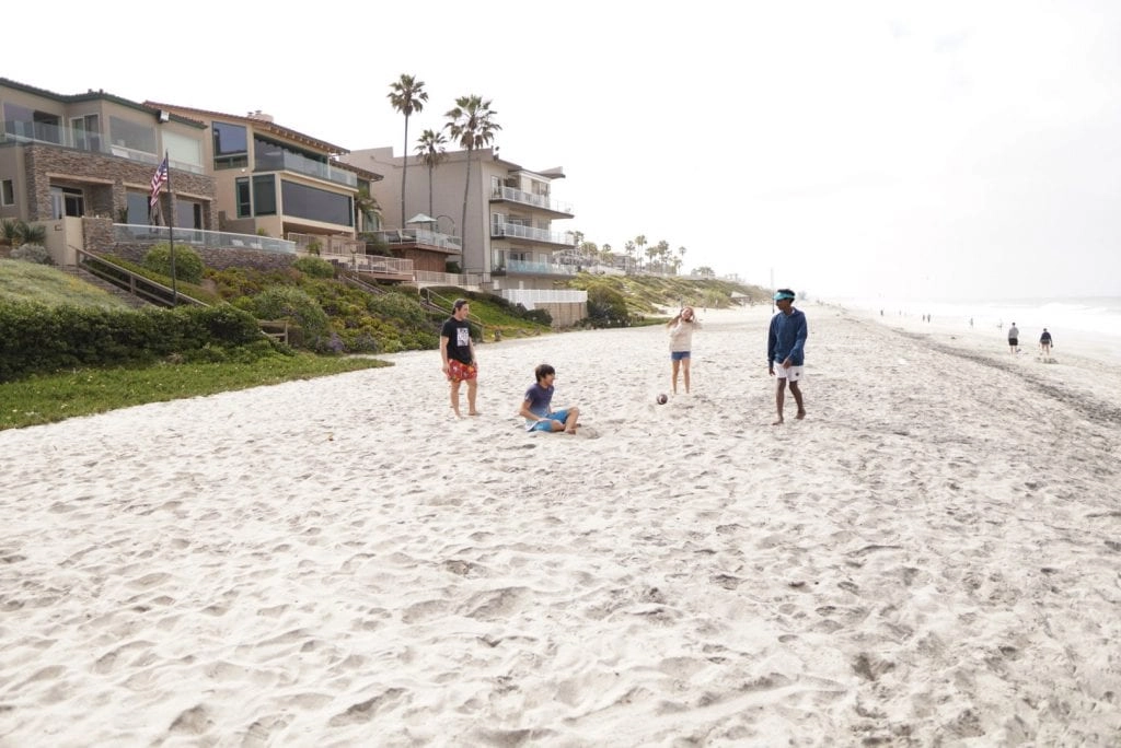 summer bucketlist for teens - 4 teens playing spikeball on the beach 