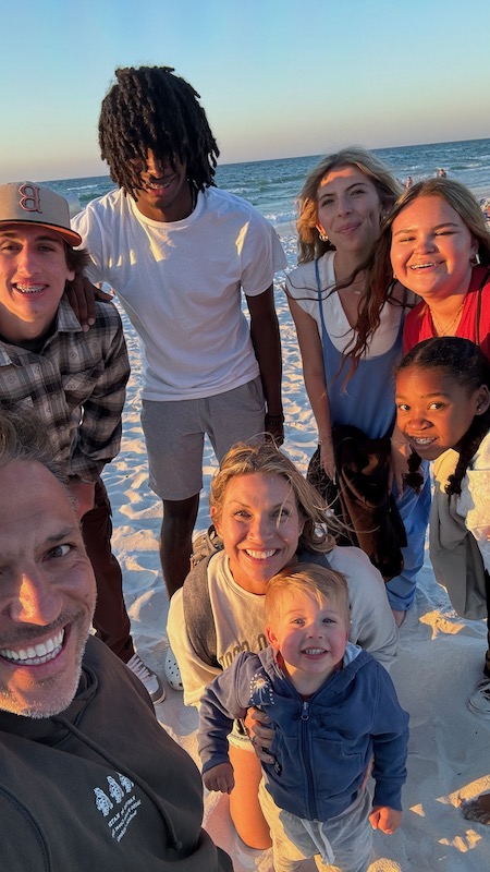 family standing on the beach at sunset