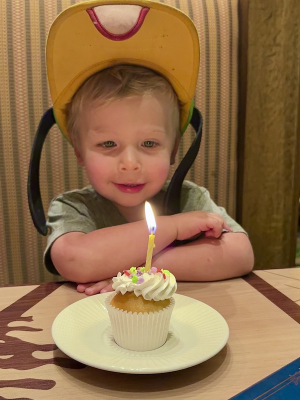 toddler blowing out candle on cupcake at Disneyland 